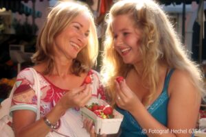 Mutter und Tochter auf dem Wochenmarkt Erdbeeren essen