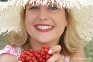 Fröhliches Lachen mit Sonnenhut und Beeren in den Händen