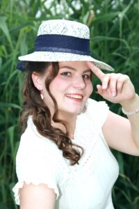 Portrait mit Hut vor grünem Schilf