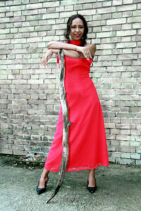 Mit rotem Kleid vor Hauswand