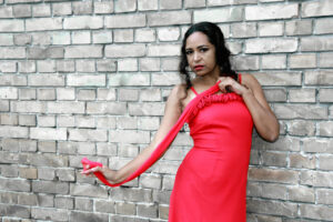 Mit rotem Kleid elegant vor Steinwand