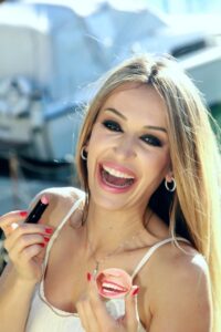 Frau mit Lippenstift hält Mund-Spiegel in der Hand. Karte als auch Spiegel als Produkt